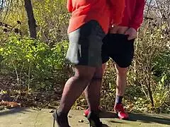 Mother-in-law assists with outdoor urination in public, wearing pantyhose and heels.