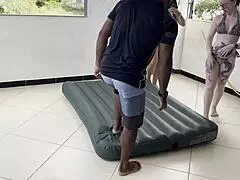 Two hotties inflate inflatable mattress with street man's help.