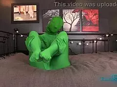 Hooded milf in full body green zentai suit engages in kinky fetish play with black housewife wearing spandex costumes